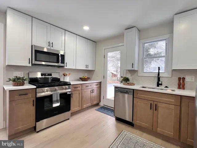 a kitchen with cabinets stainless steel appliances a sink and a window