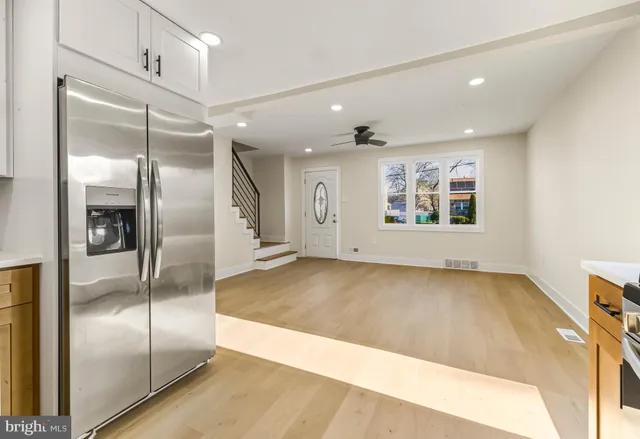 a view of a hallway with stainless steel appliances kitchen island granite countertop a refrigerator and a sink