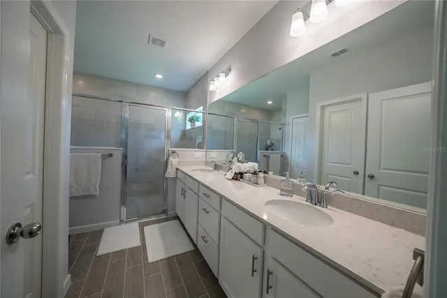 a bathroom with a double vanity sink mirror and shower