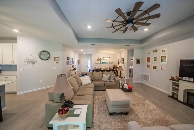 a living room with furniture kitchen view and a wooden floor