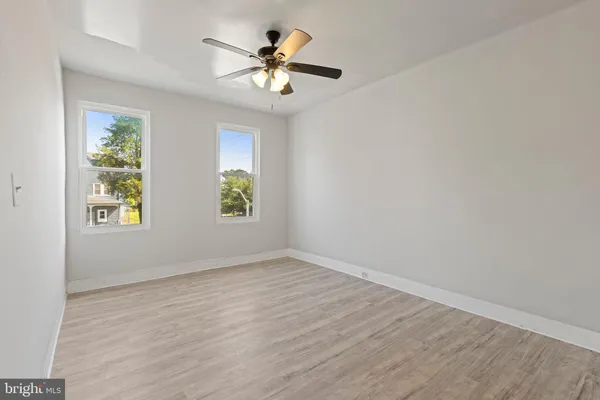 an empty room with windows and chandelier fan