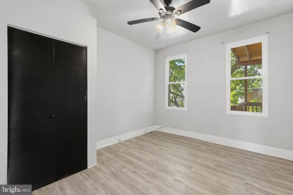 an empty room with wooden floor closet and windows