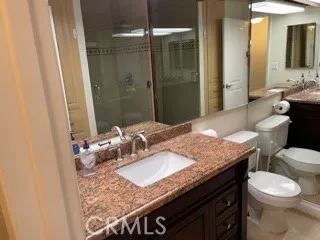 a bathroom with a granite countertop sink a toilet and shower
