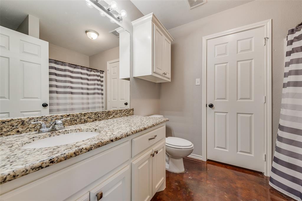 309 East 2nd Street Maypearl, TX 76064 - Photo 12 of 20 a bathroom with a granite countertop sink a toilet and a window