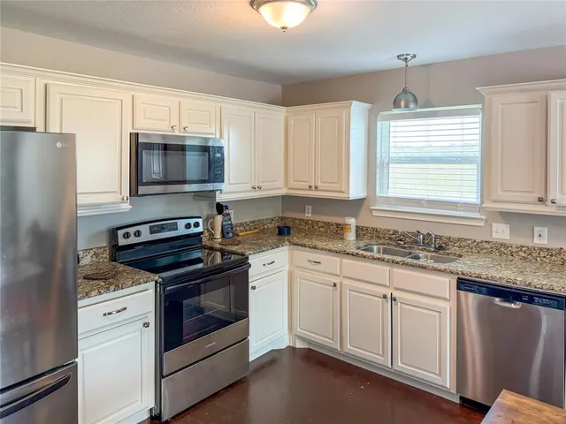 a kitchen with granite countertop white cabinets white stainless steel appliances and a sink