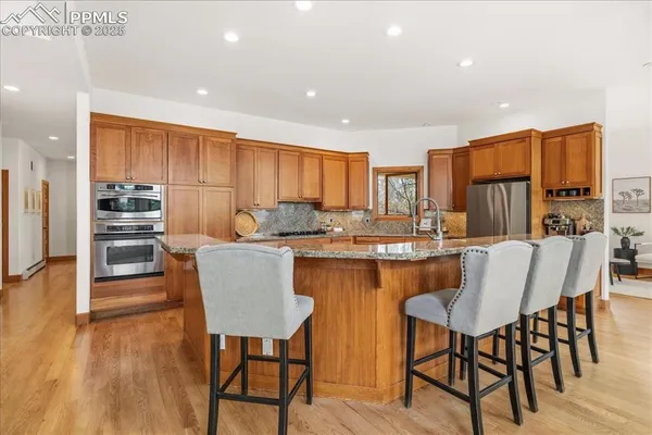 a kitchen with stainless steel appliances granite countertop a sink a refrigerator and wooden cabinets