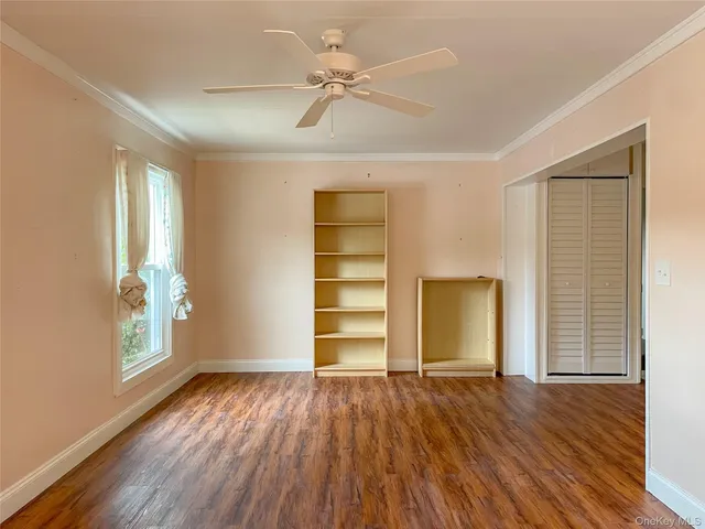an empty room with wooden floor closet chandelier fan and windows
