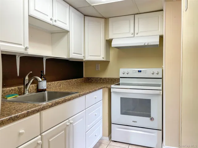 a kitchen with granite countertop white cabinets and white appliances