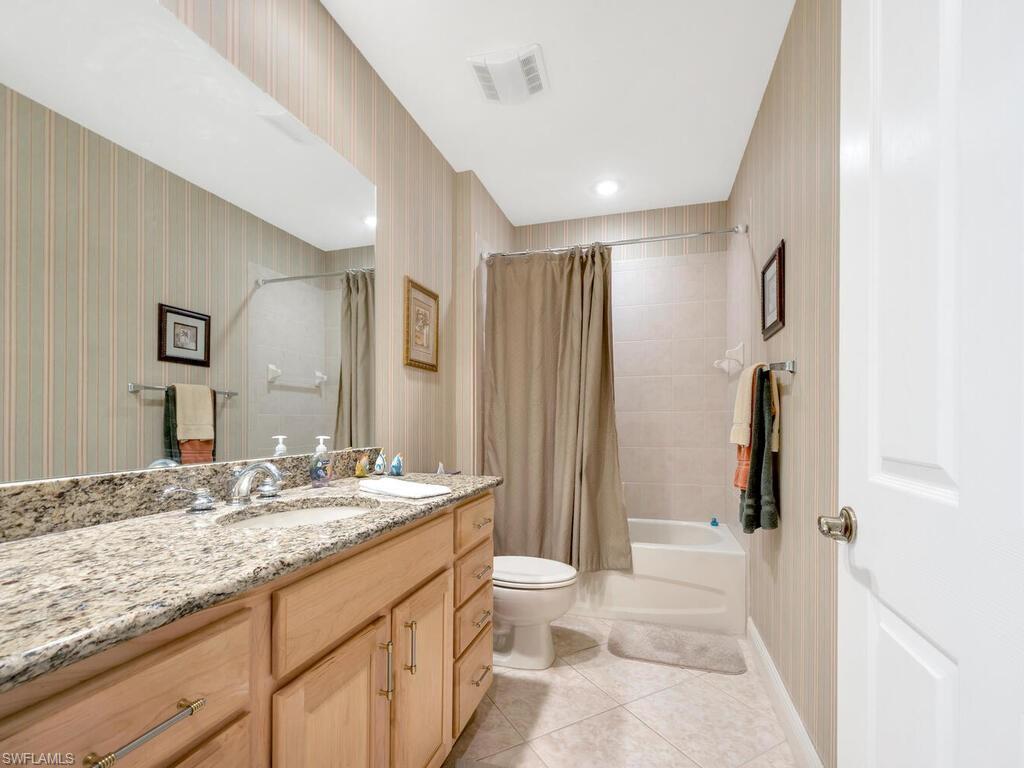 10540 Marino Pointe Drive, Unit 301 Miromar Lakes, FL 33913 - Photo 15 of 43 a bathroom with a granite countertop sink toilet and shower