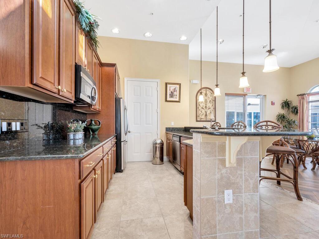 10540 Marino Pointe Drive, Unit 301 Miromar Lakes, FL 33913 - Photo 21 of 43 a kitchen with stainless steel appliances granite countertop a refrigerator a stove and a sink with wooden floor