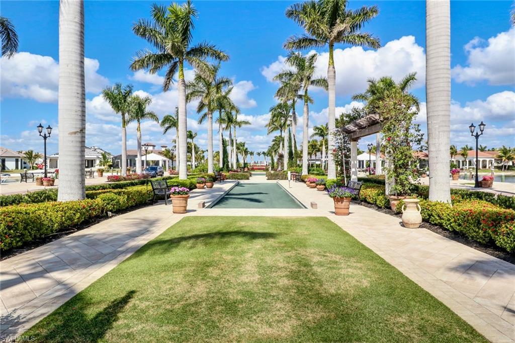 10540 Marino Pointe Drive, Unit 301 Miromar Lakes, FL 33913 - Photo 41 of 43 a view of a swimming pool with a lawn chairs and palm trees
