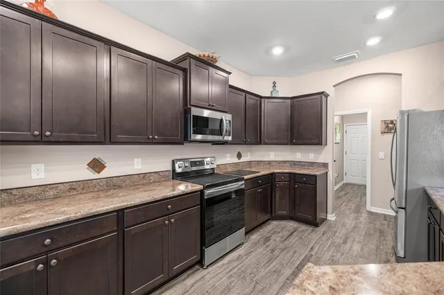 a kitchen with granite countertop stainless steel appliances a sink cabinets and wooden floor