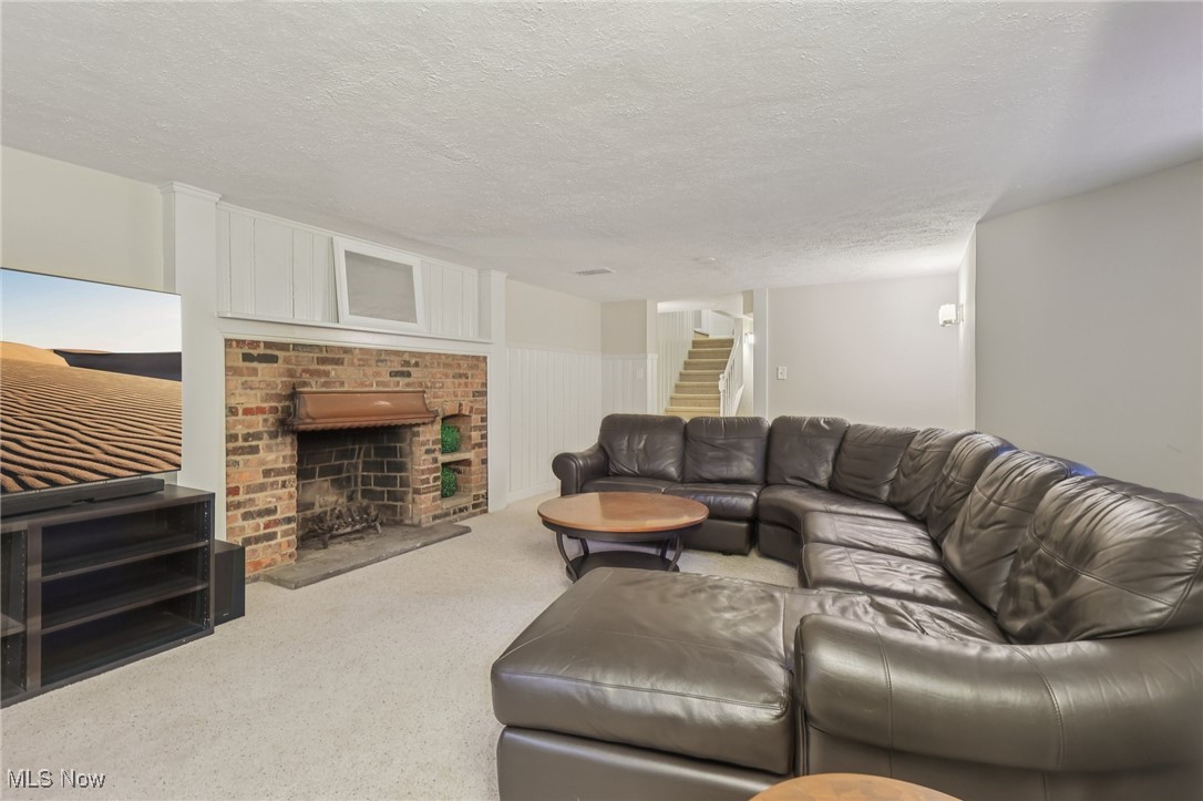 17024 Fernway Road Cleveland, OH 44120 - Photo 40 of 46 Recreation Room featuring a textured ceiling, a brick fireplace, carpet flooring, and stairs