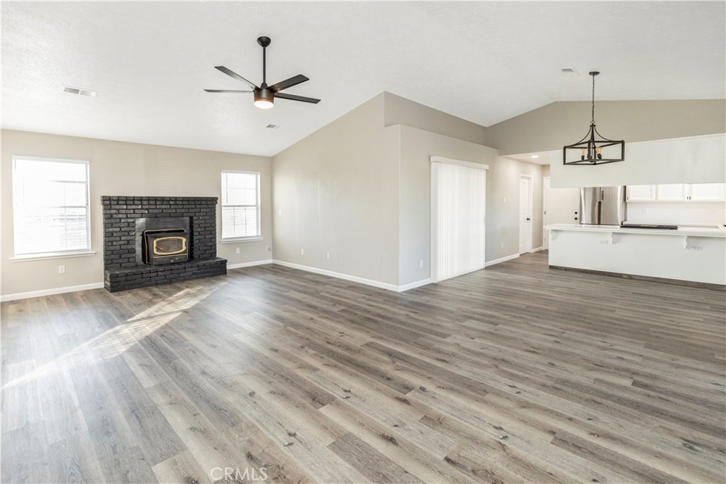 28702 Rancho Avenue Madera, CA 93638 - Photo 8 of 34 an empty room with windows fireplace and wooden floor