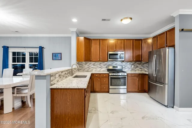 a large kitchen with granite countertop a large counter top stainless steel appliances and cabinets