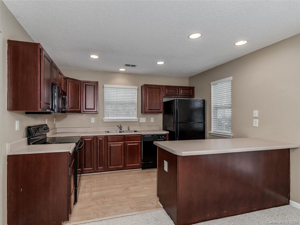 8376 Rudolph Road Charlotte, NC 28216 - Photo 9 of 17 a large kitchen with stainless steel appliances granite countertop a stove top oven a sink dishwasher and a refrigerator with wooden cabinets