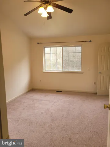 an empty room with a chandelier fan and windows
