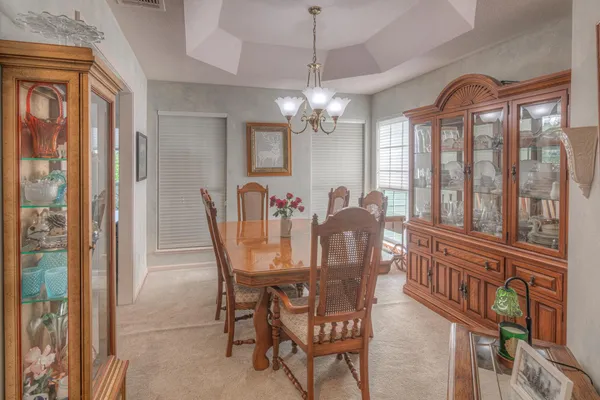 a view of a dining room with furniture a chandelier and large window