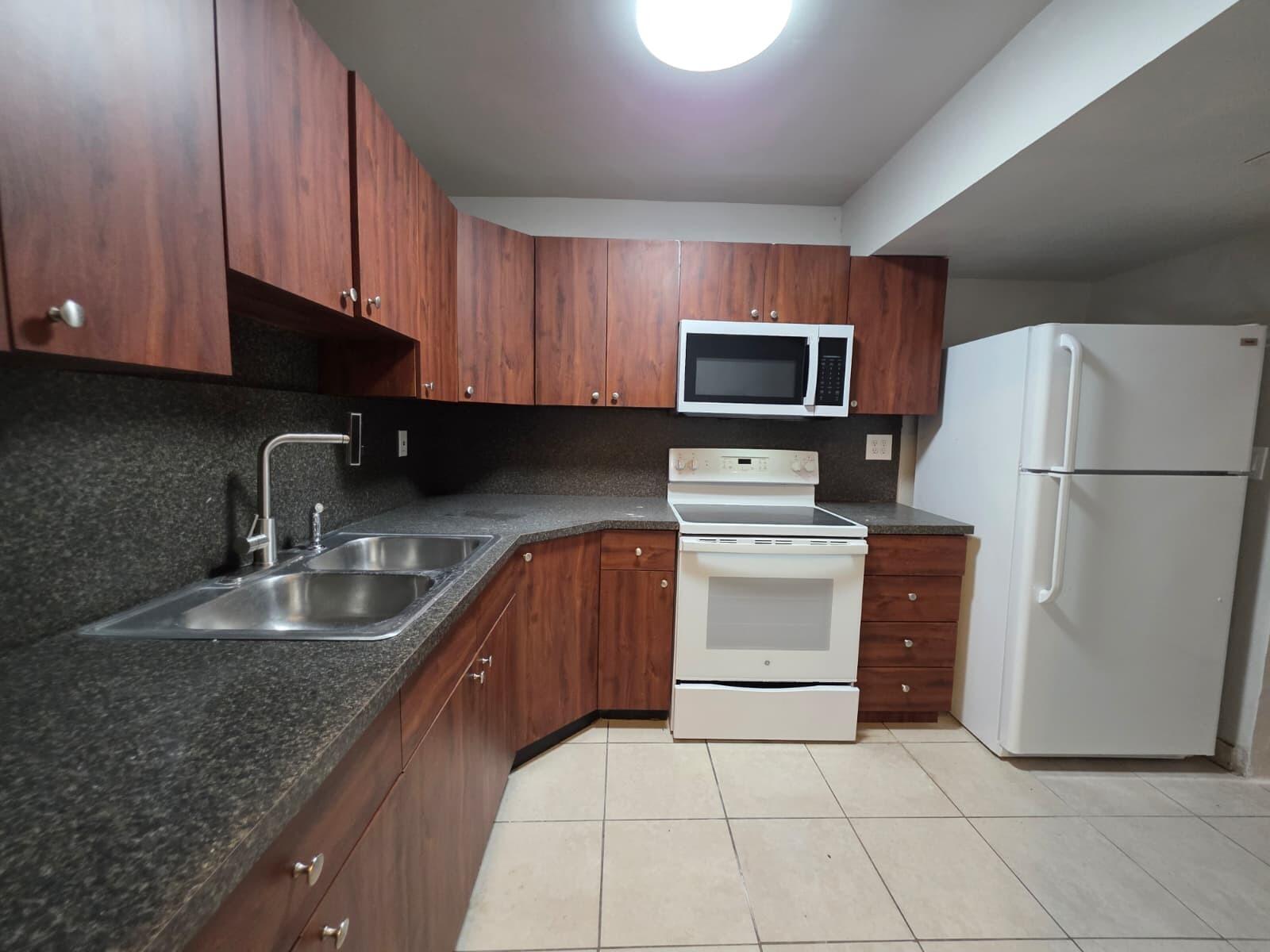 2767 Northwest 58th Terrace Lauderhill, FL 33313 - Photo 3 of 8 a kitchen with granite countertop a refrigerator and a stove top oven