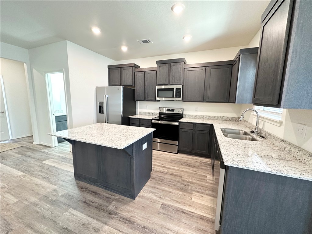 959 South Rupple Road, Unit 4 Fayetteville, AR 72704 - Photo 9 of 25 The kitchen features a central island with a granite countertop, dark wood cabinetry, and stainless steel appliances