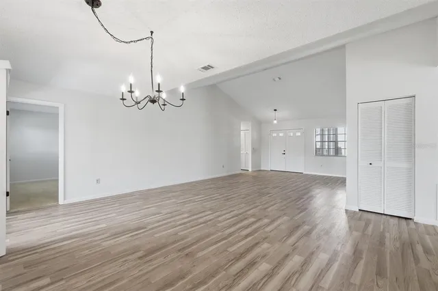 a view of an empty room with wooden floor and window