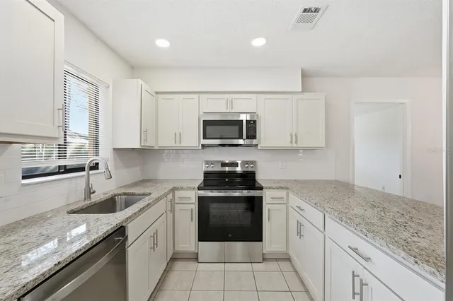 a kitchen with granite countertop white cabinets and a stove top oven