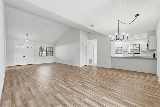a view of an empty room with kitchen and window