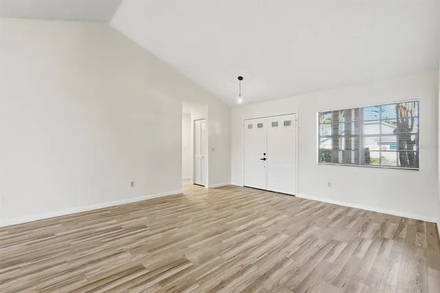 a view of an empty room with wooden floor and a window