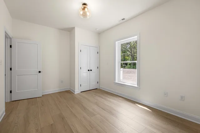 an empty room with wooden floor chandelier fan and windows