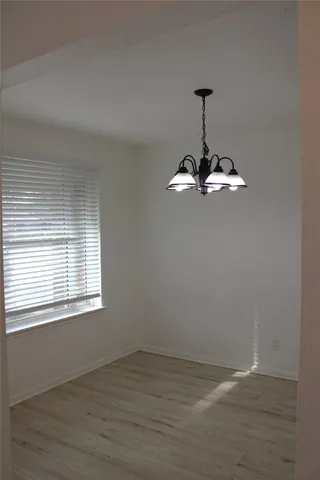 a view of empty room with wooden floor and window