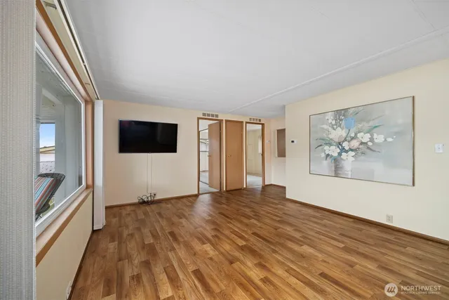 a view of an empty room with a window and wooden floor