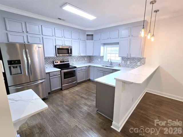 a kitchen with granite countertop a refrigerator a sink a stove a microwave and island