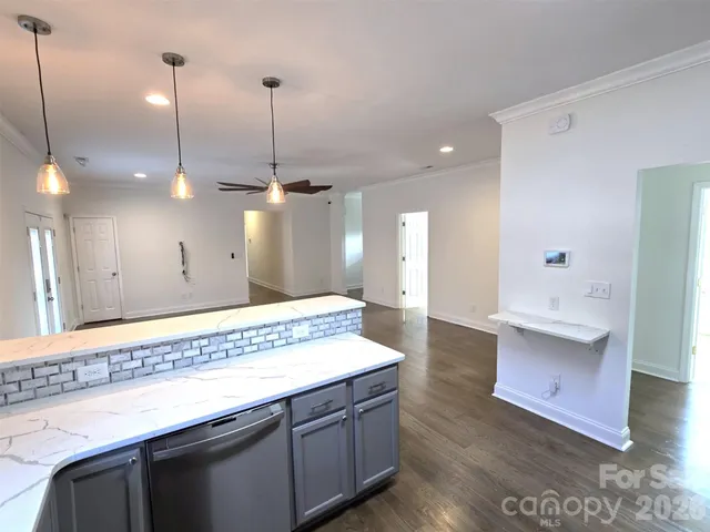 a view of an empty room with wooden floor and a ceiling fan