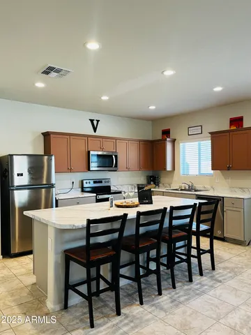 a kitchen with stainless steel appliances kitchen island granite countertop a table chairs sink and cabinets