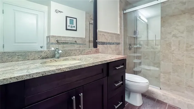 a bathroom with a granite countertop sink toilet and shower