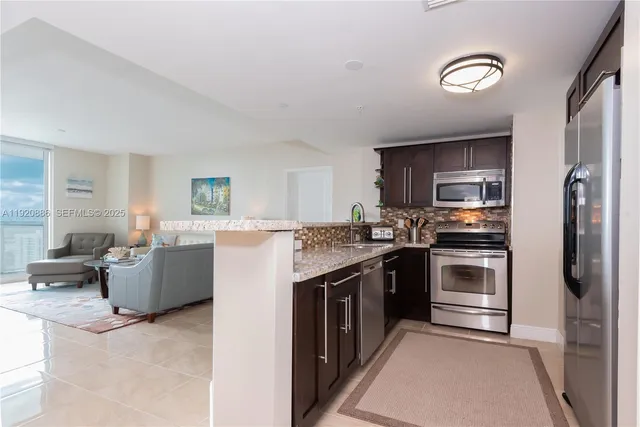 a kitchen with stainless steel appliances granite countertop a stove top oven a sink dishwasher a refrigerator and a cabinets