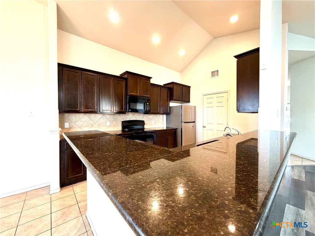 500 Obsidian Lane Jarrell, TX 76537 - Photo 12 of 33 a kitchen with stainless steel appliances granite countertop a sink a stove and a microwave