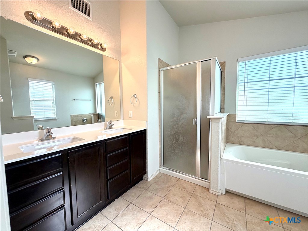 500 Obsidian Lane Jarrell, TX 76537 - Photo 23 of 33 a bathroom with a double vanity sink a mirror and a bathtub