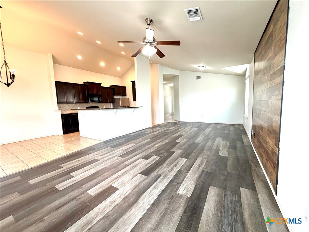 500 Obsidian Lane Jarrell, TX 76537 - Photo 9 of 33 a view of a kitchen with kitchen island a sink wooden floor and a living room