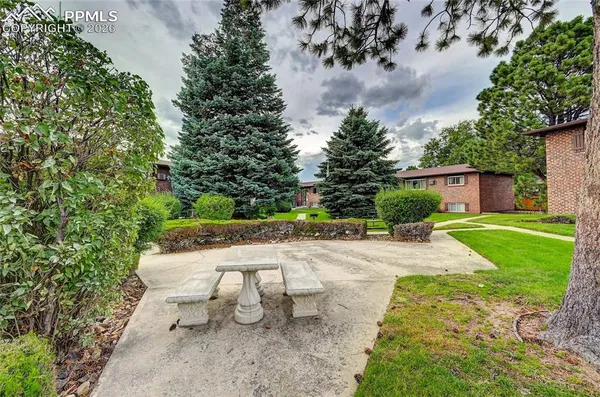 a view of a backyard with table and chairs plants and large trees
