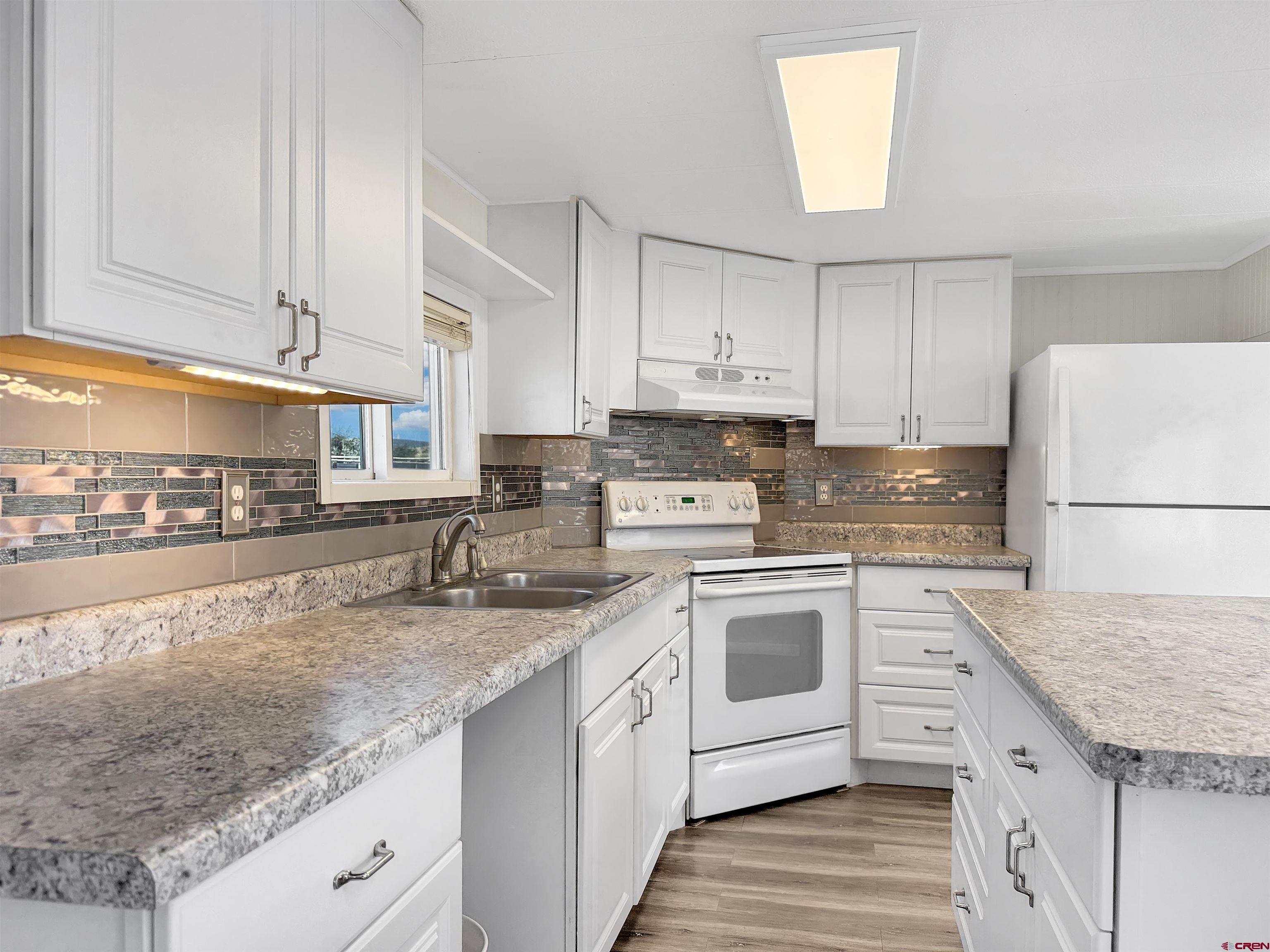 5057 Peach Valley Road Delta, CO 81416 - Photo 6 of 22 a kitchen with granite countertop a sink stainless steel appliances and white cabinets