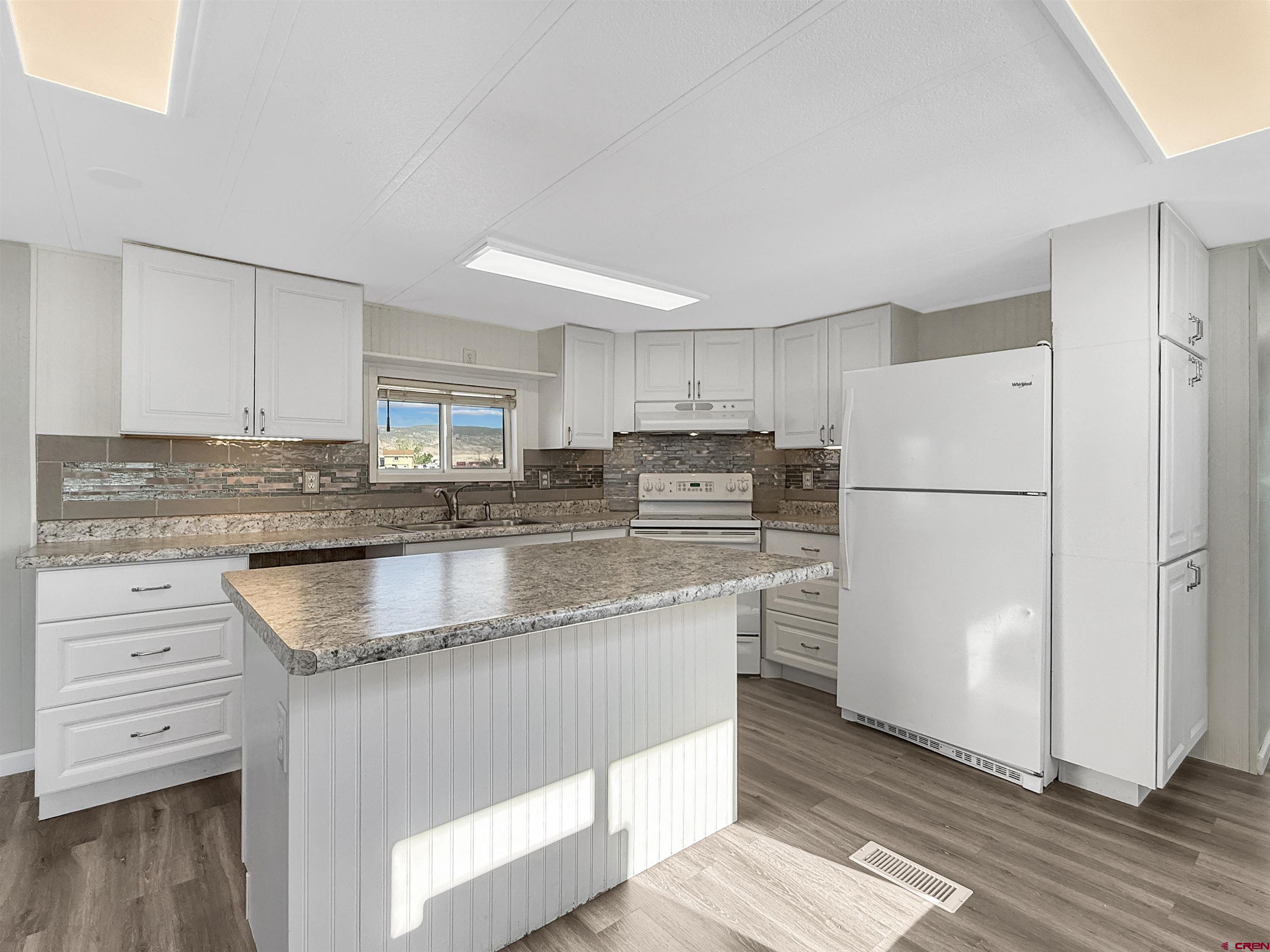 5057 Peach Valley Road Delta, CO 81416 - Photo 7 of 22 a kitchen with stainless steel appliances granite countertop a refrigerator a stove a sink and white cabinets