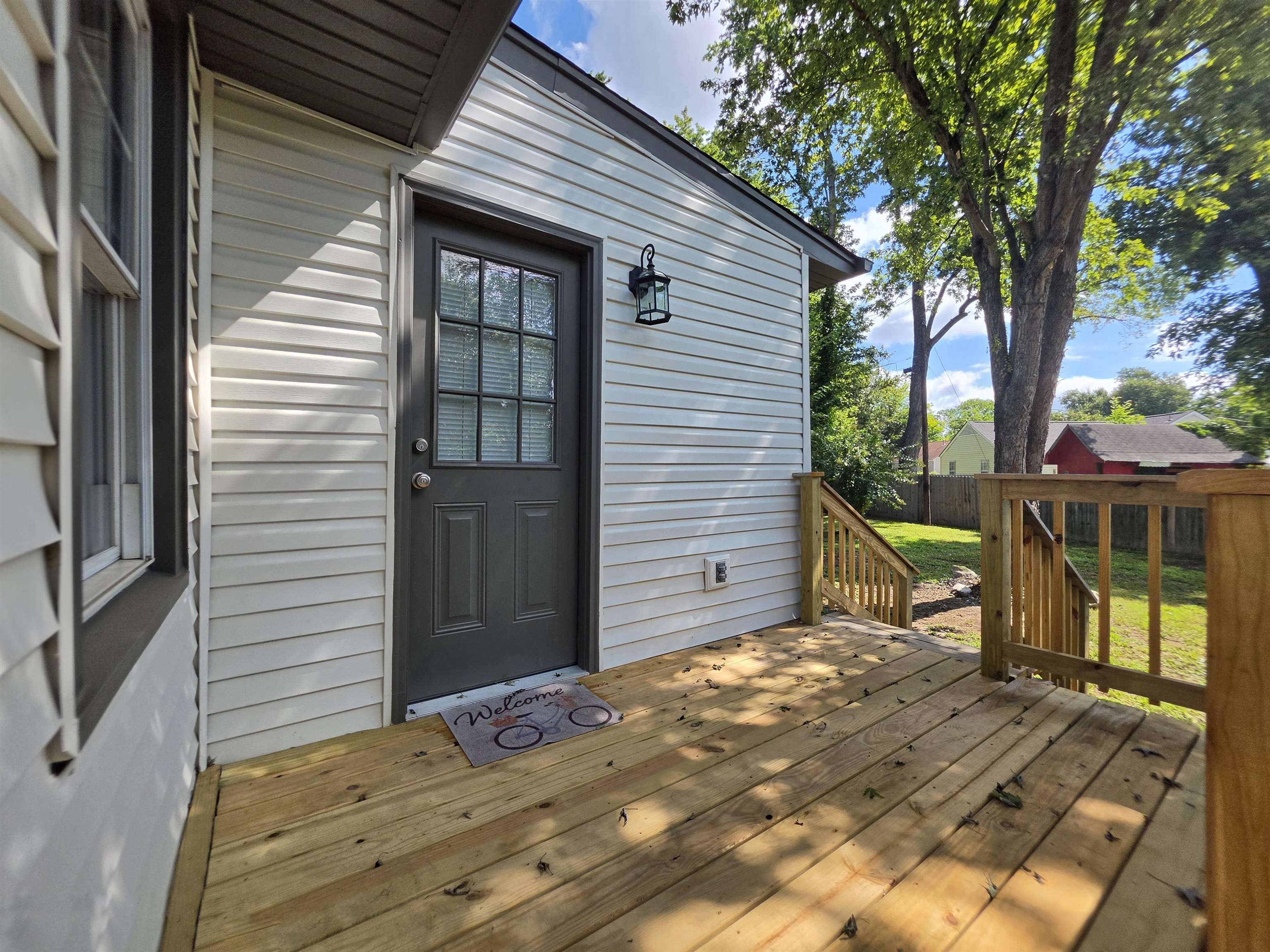 7966 Martha Road Millington, TN 38053 - Photo 24 of 26 Exterior siding with a window and a dark gray entry door featuring multiple glass panes, complemented by a wall-mounted lantern light fixture