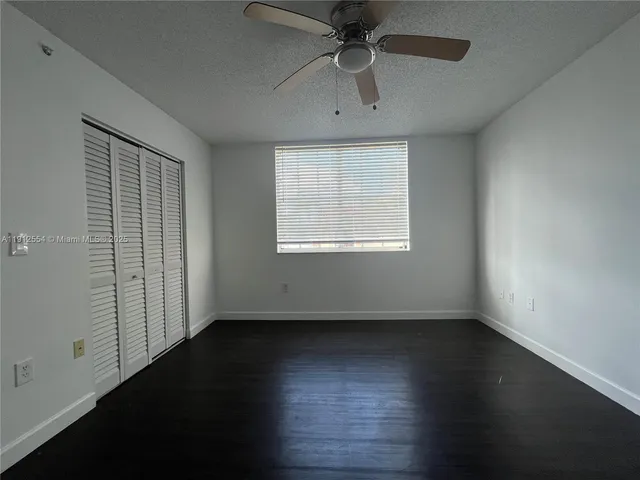 an empty room with wooden floor chandelier fan and windows