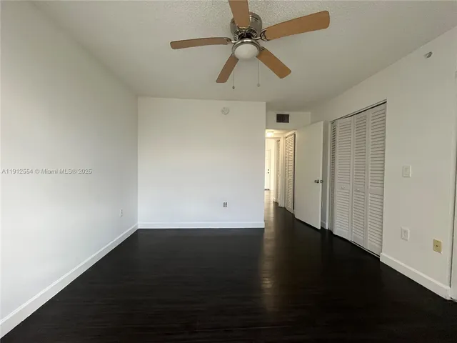 an empty room with wooden floor fan and windows