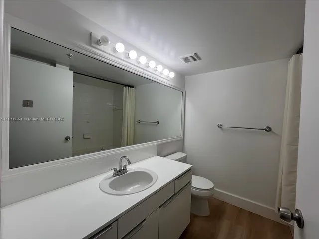 a bathroom with a granite countertop sink toilet and a mirror