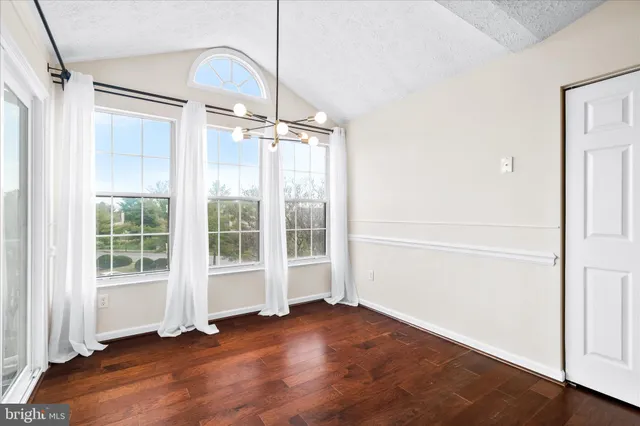 an empty room with wooden floor a glass door and shower