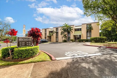 a front view of a house with a yard and a large tree