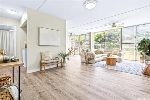 a living room with furniture large windows and wooden floor