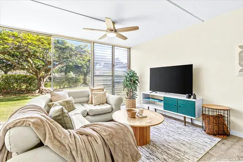 a living room with furniture a flat screen tv and a large window